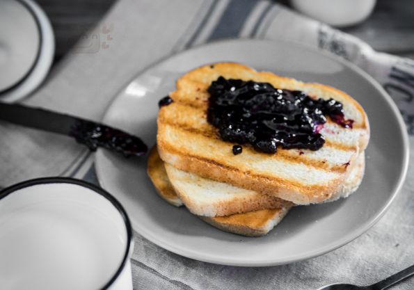 Toasted bread with jam and milk on wooden background