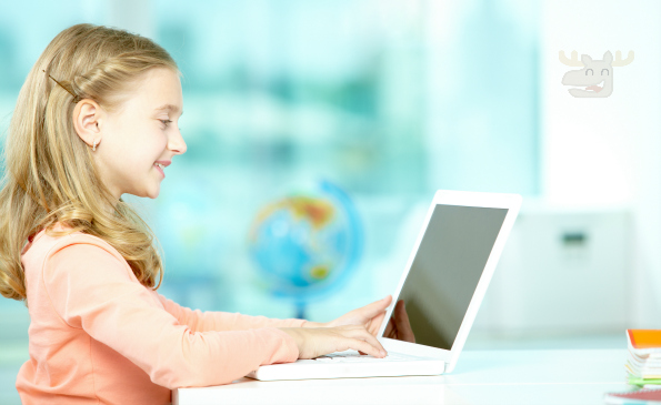 Portrait of smart schoolgirl sitting in classroom and typing